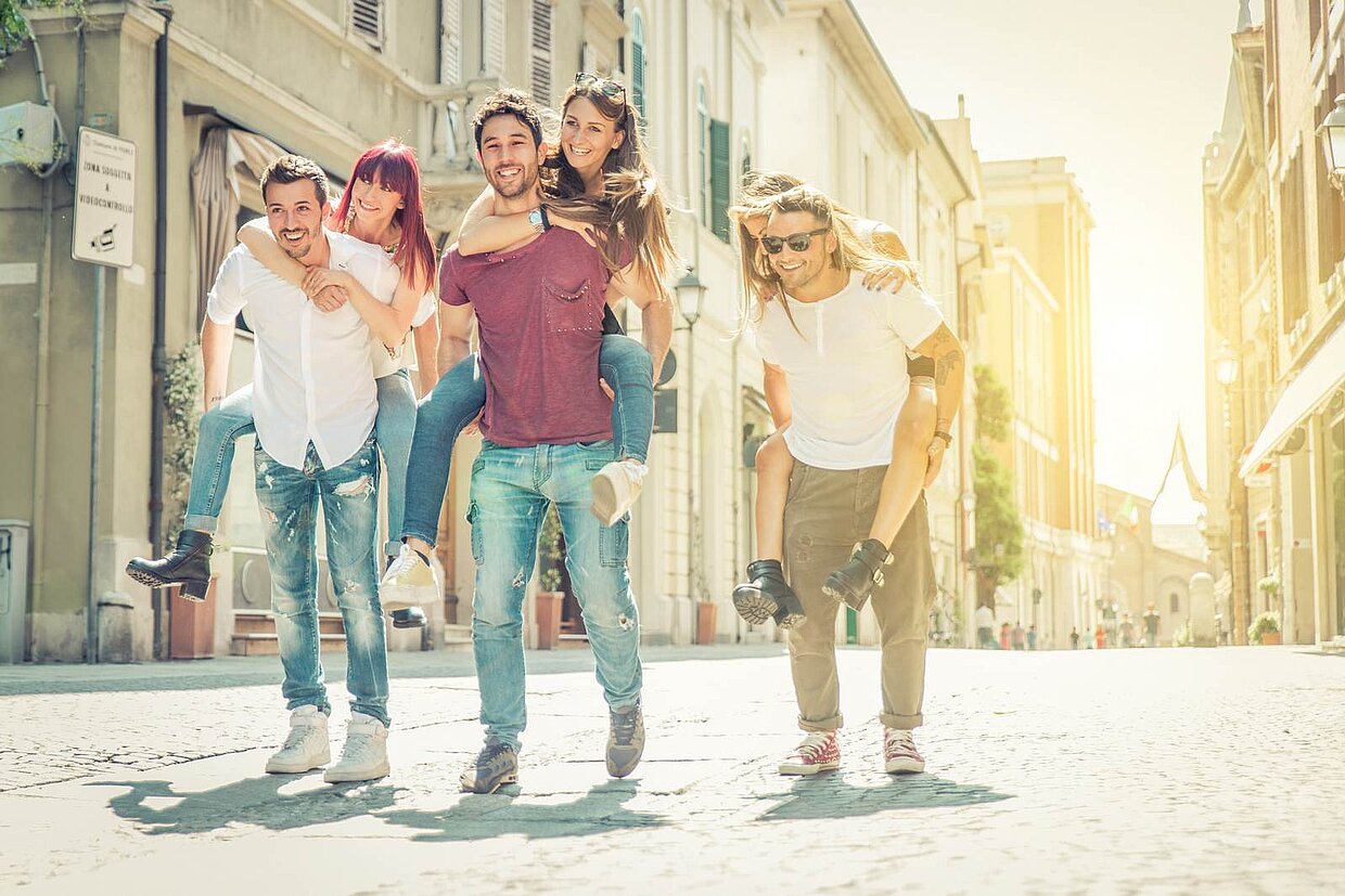 3 Menschen auf drei Menschen rennen Huckepack nebeneinander auf einer Straße