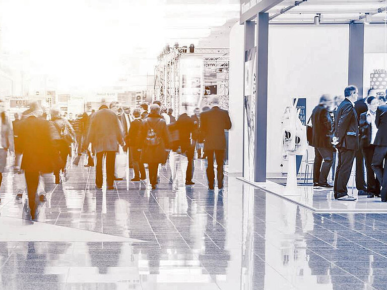 Messehalle mit Ständen und Besuchern